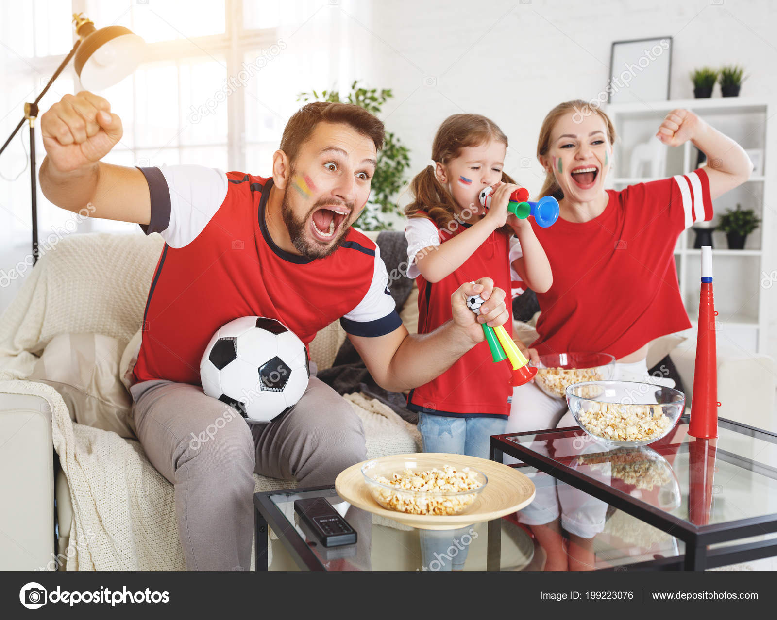 family of fans watching a football match on TV at home